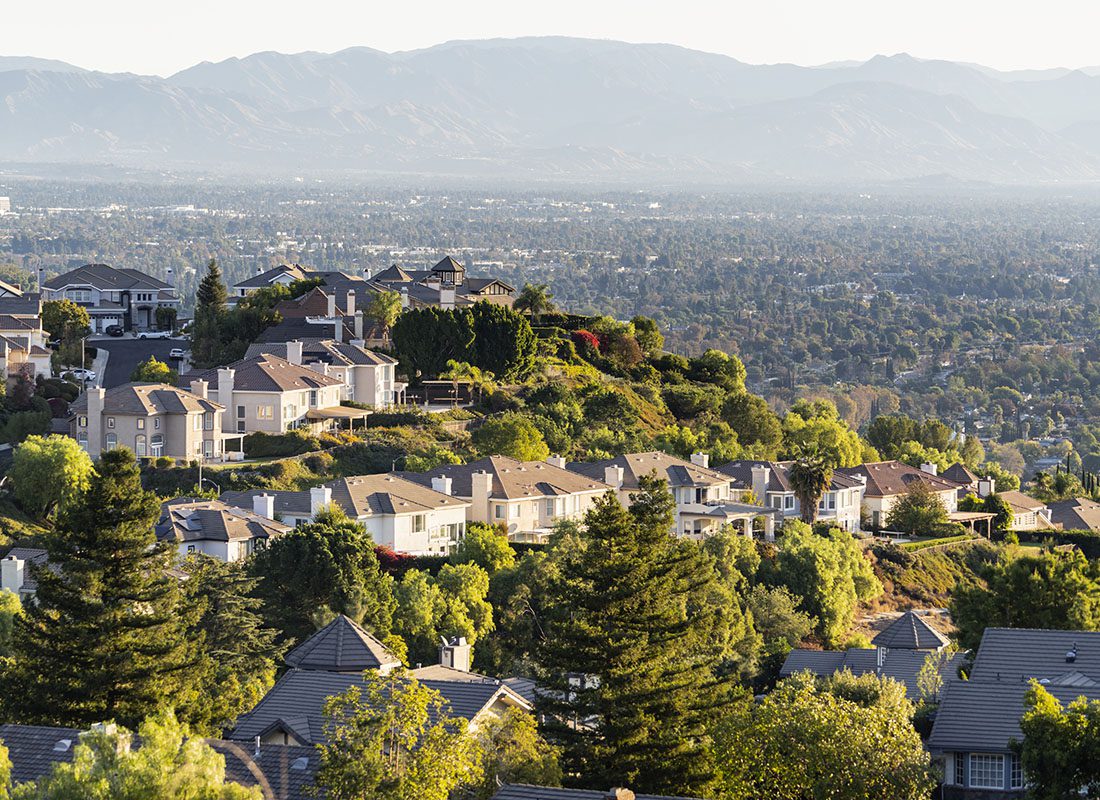 Insurance Solutions - View of Luxury Homes on a Hillside in Los Angeles Surrounded by Green Trees on a Sunny Day with Mountains in the Background